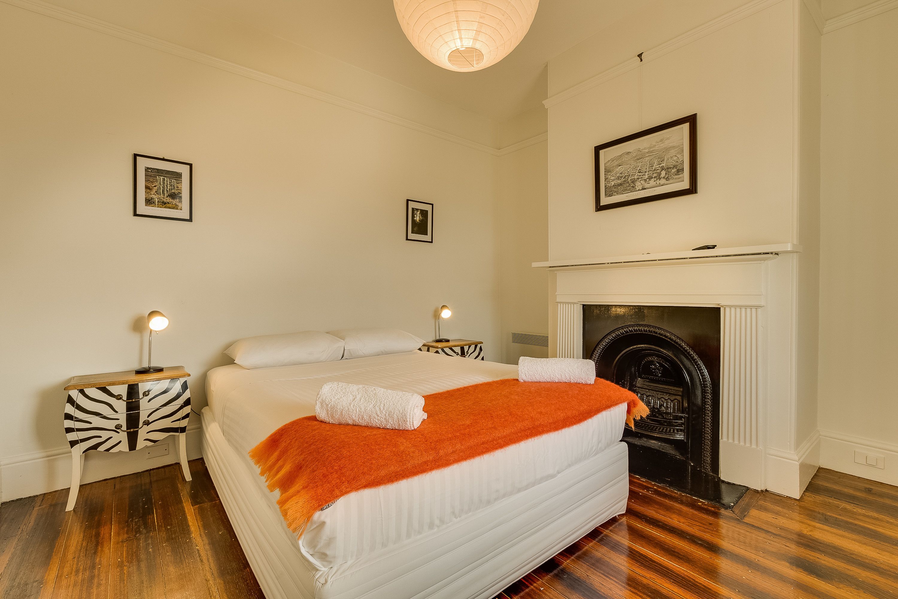A bedroom with a large bed, a fireplace, and a zebra-patterned nightstand.