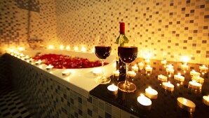 Uma banheira com velas e dois copos de vinho tinto.