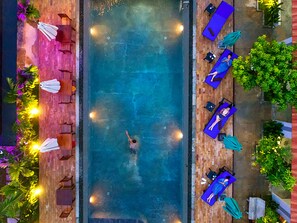 An aerial view of a swimming pool with lounge chairs and umbrellas, surrounded by greenery. - Lilly Holiday Hotel (Siem Reap)