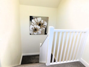 A staircase with a white railing and a painting of flowers on the wall.