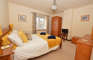 A bedroom with a bed, a wooden wardrobe, a television, and a desk with a lamp. - Cockleshell Cottage  - superb, traditional flint cottage in an enviable position yards from the sea. (Sheringham)