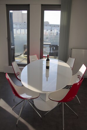 Meetings and social gatherings take place around the round table, with a city view visible through the large windows.