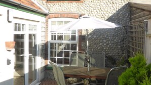 Eine Terrasse mit Tisch und Stühlen, einem weißen Sonnenschirm und einer Steinmauer.