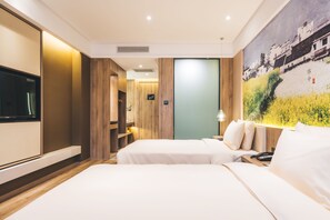 Une chambre d’hôtel avec deux lits, une télévision, un tableau et une armoire en bois.