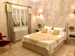 A hotel room with a bed, a chair, a nightstand, a lamp, and a window with curtains.