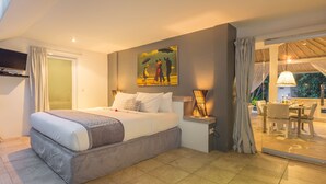 A modern hotel room with a large bed, a painting on the wall, a dining area with a table and chairs, and a view of the outdoors. - Villa Esha Drupadi I (Seminyak)
