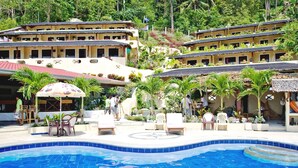 A hotel with a swimming pool, outdoor seating, and lush greenery. - Oriental Sabang Hill Resort (Puerto Galera)
