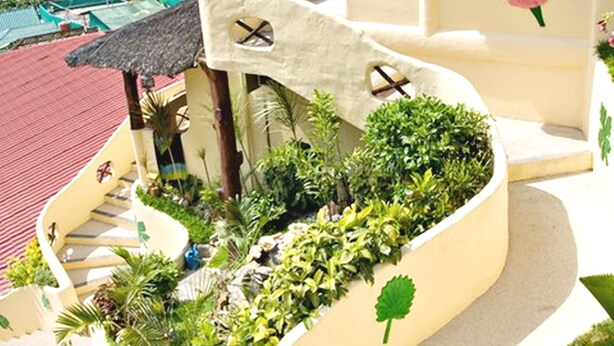 A curved staircase with a garden planter, a thatched roof structure, and a view of the sea. - Oriental Sabang Hill Resort (Puerto Galera)