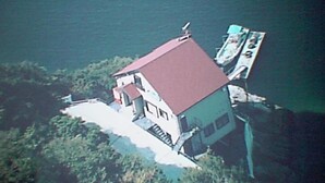 A house with a red roof, situated on a cliff overlooking a body of water. - Seaside Uwakai (Seiyo)