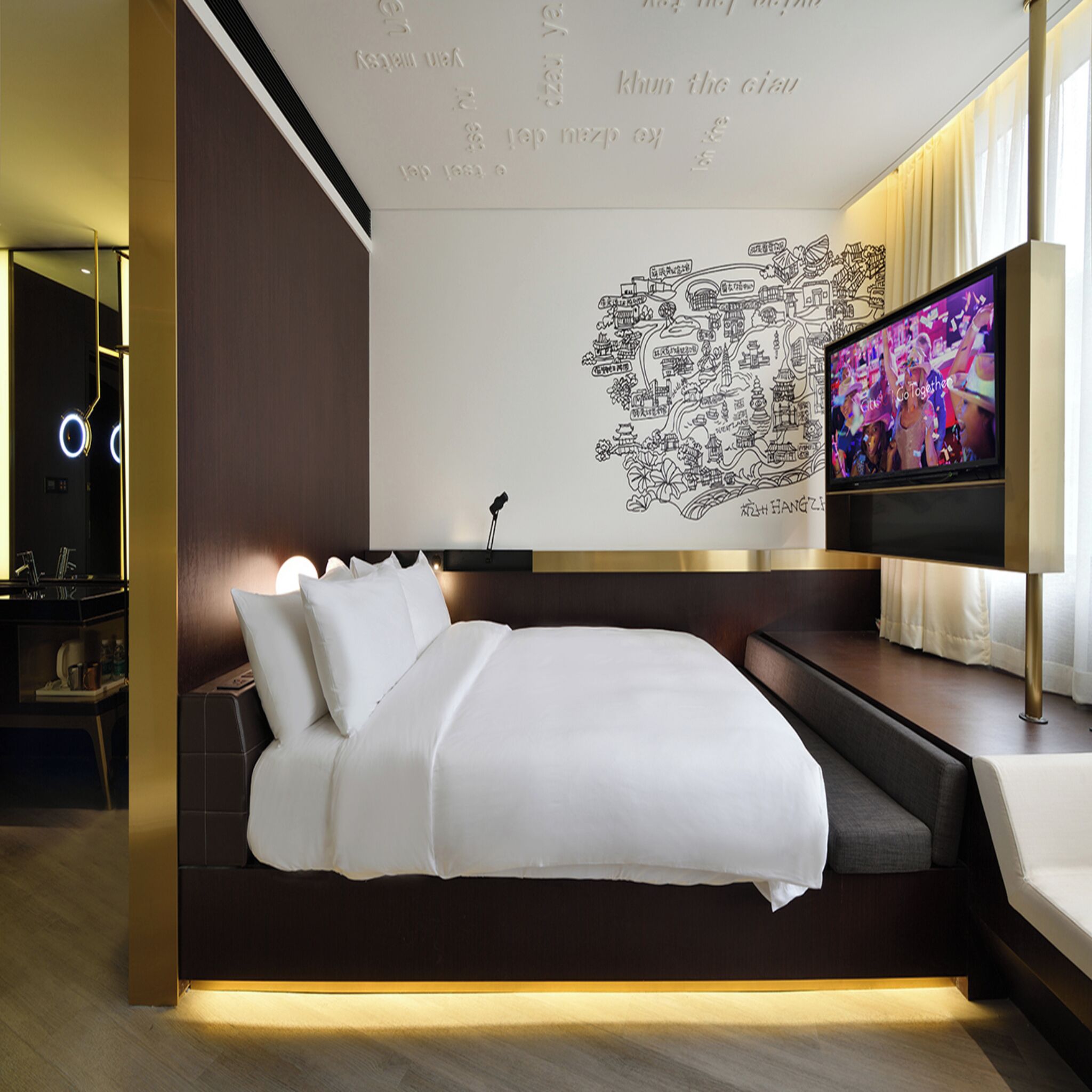 A modern hotel room with a large bed, a flat-screen TV, and a wall map.