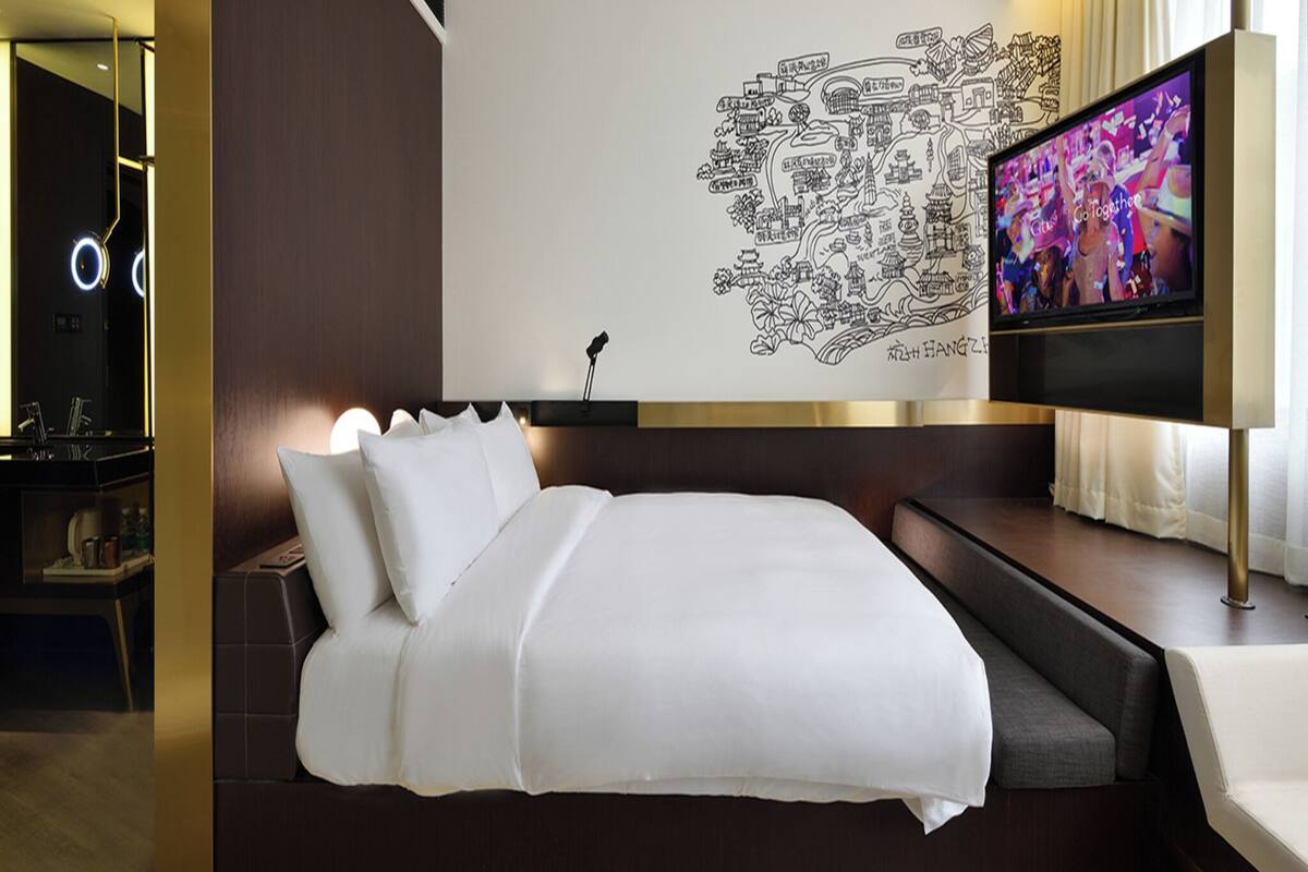 Ein modernes Hotelzimmer mit einem großen Bett, einem Flachbildfernseher und einer Wandkarte.