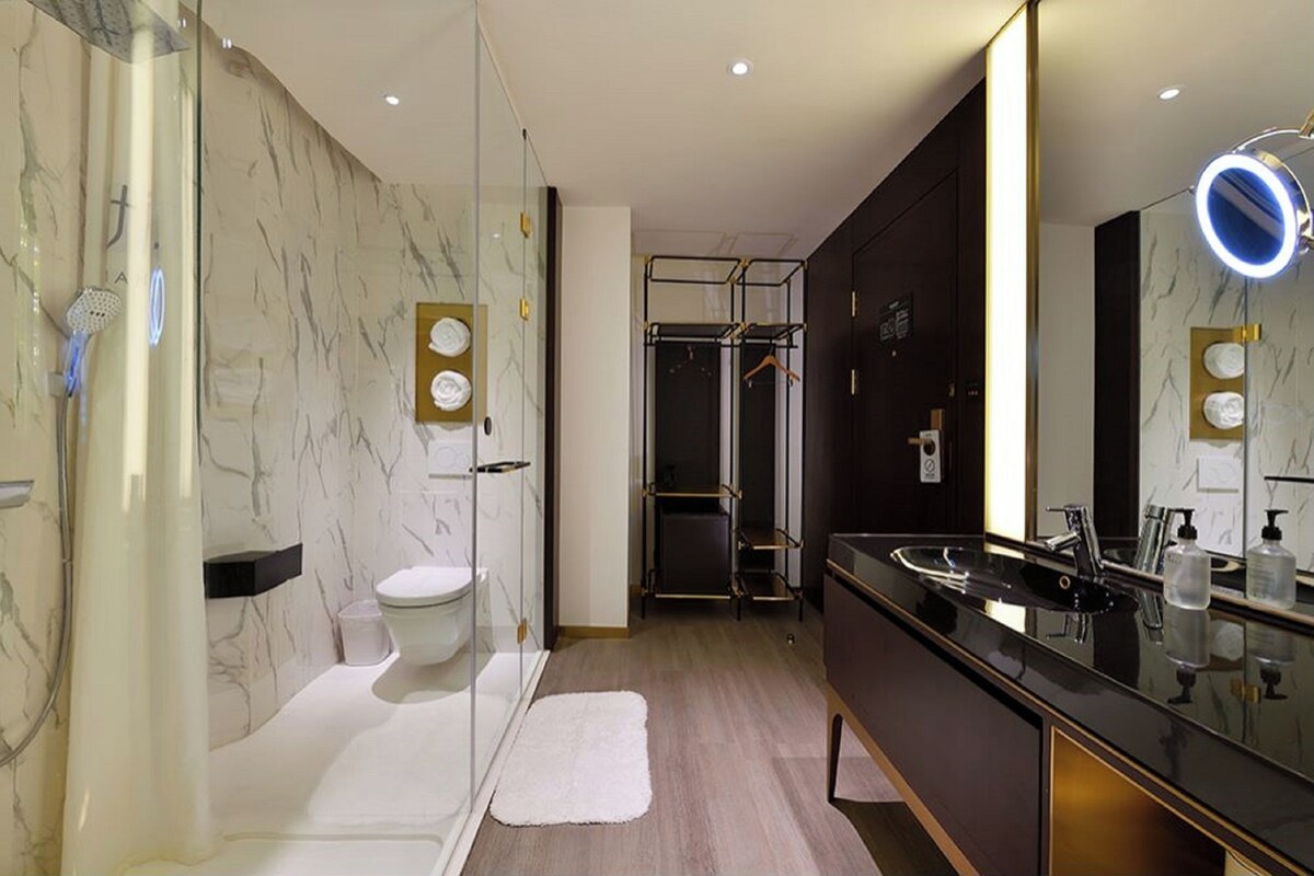 A modern bathroom with a glass shower, a toilet, a vanity with a mirror, and a towel rack.