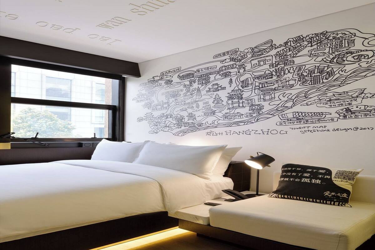 Ein Hotelzimmer mit einer großen Wandkarte, einem Bett, einem Nachttisch und einer kleinen Couch.