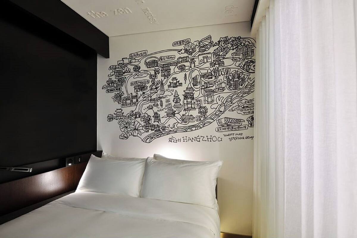 Ein Hotelzimmer mit Bett, Wandgemälde und einem Vorhangfenster.