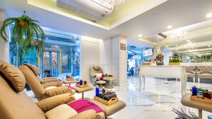 A modern spa area with massage chairs, a reception desk, and a view of the outside.