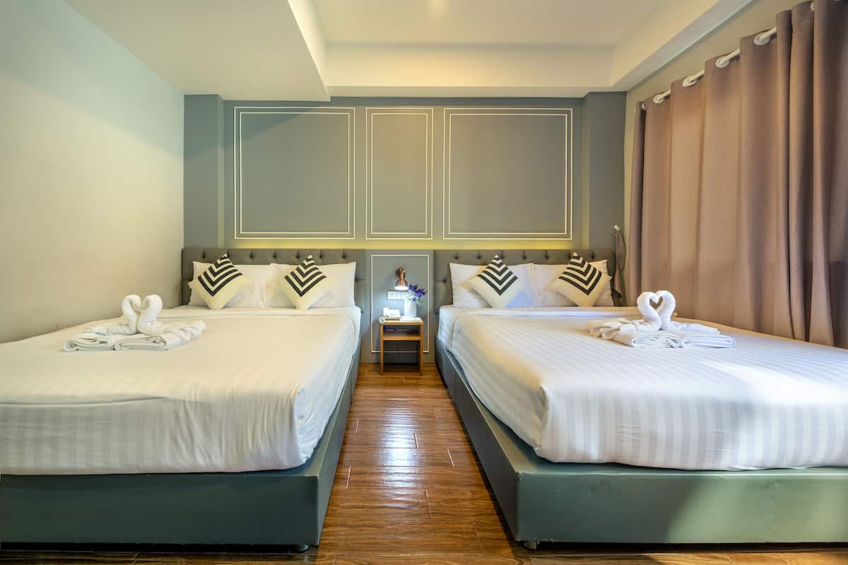 Une chambre d’hôtel avec deux lits, une table de chevet et un miroir au-dessus des lits.