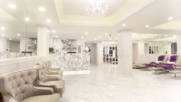 A spacious lobby with a marble reception desk, plush seating, and a chandelier.