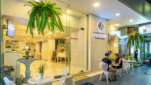 A hotel entrance with a reception desk, seating area, and a sign for 'Paris I Room'.