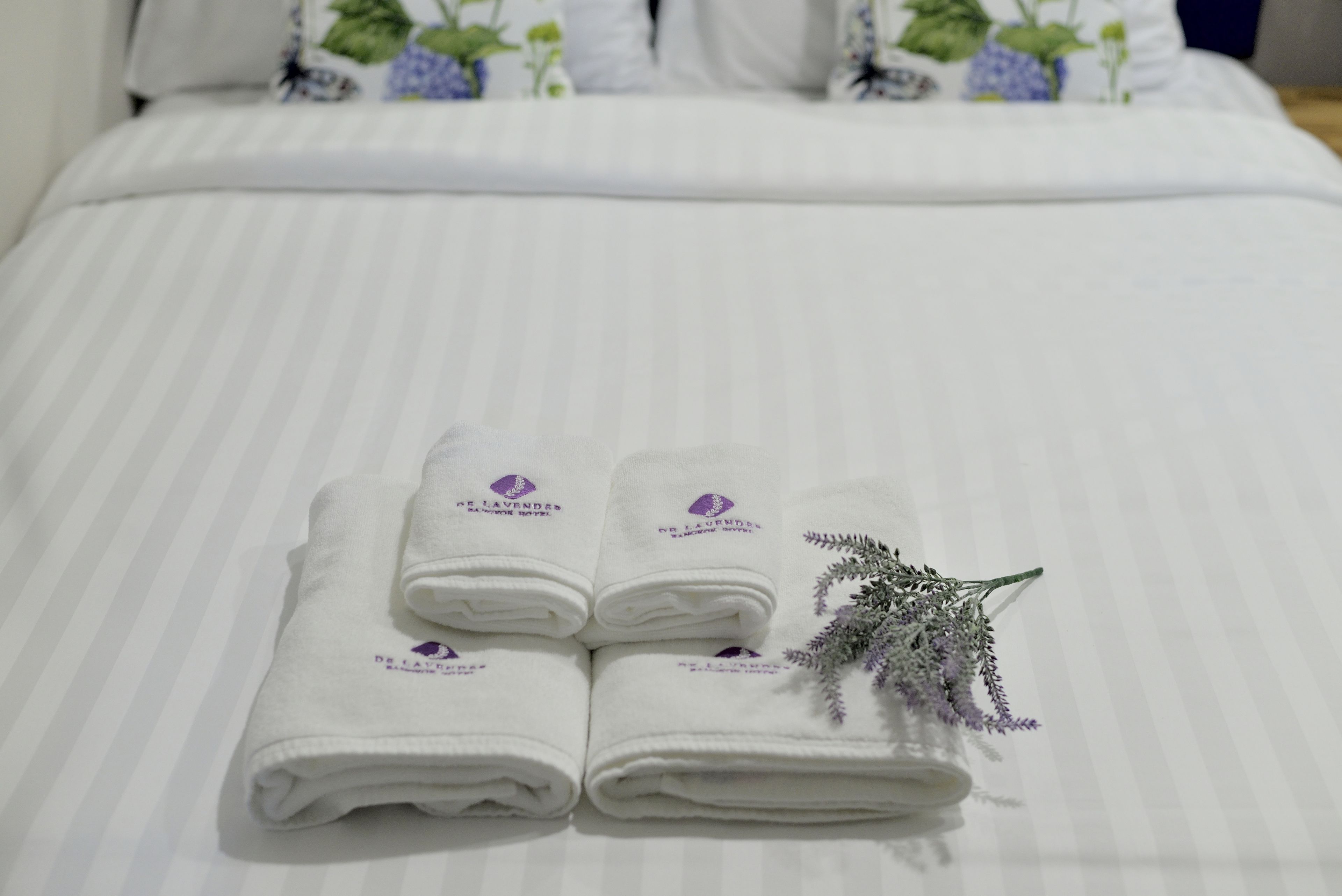 A neatly made bed with white linens and a decorative lavender sprig.