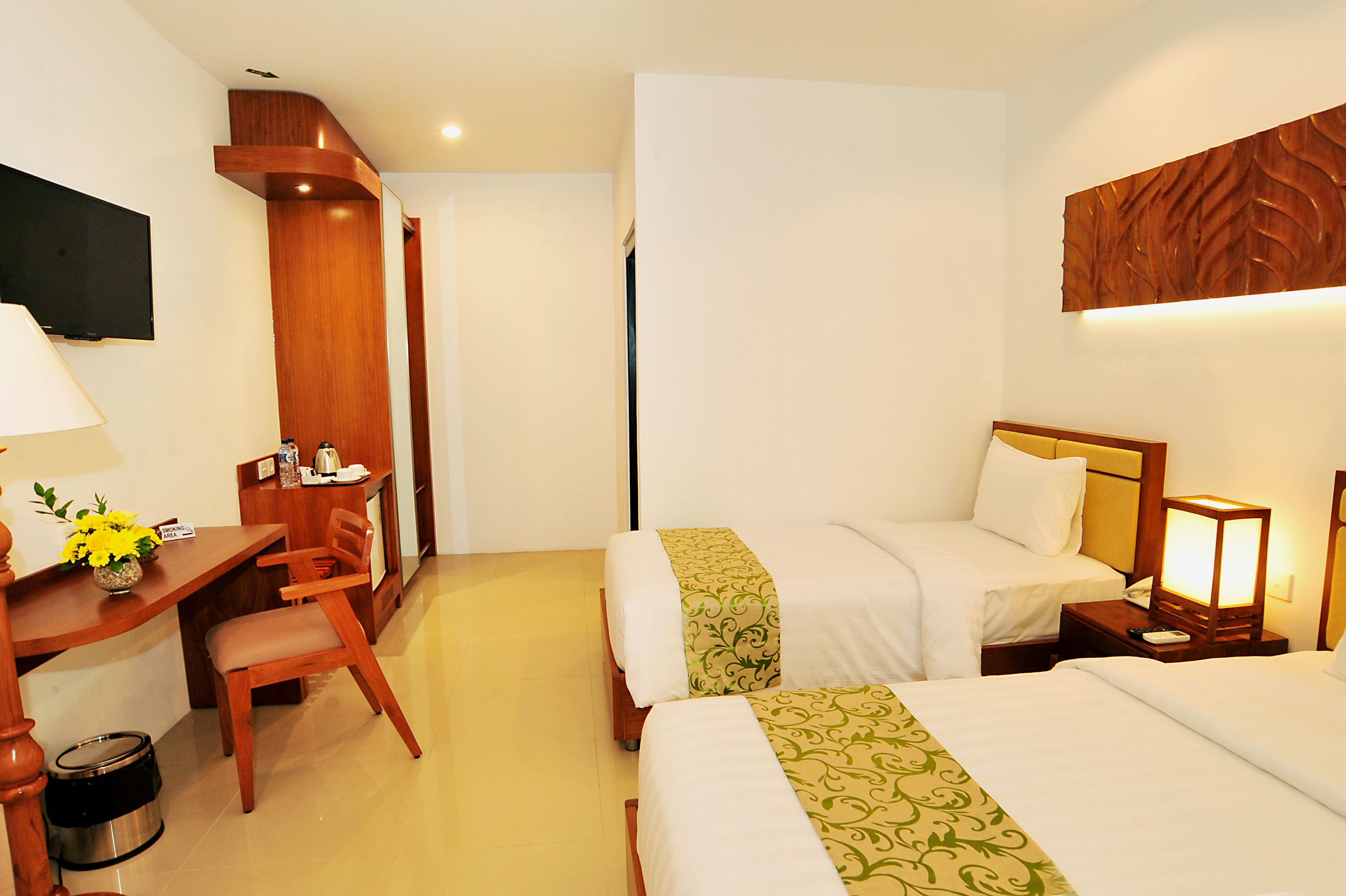 Une chambre d’hôtel avec deux lits, un bureau, une chaise, une télévision et une table de chevet avec une lampe.