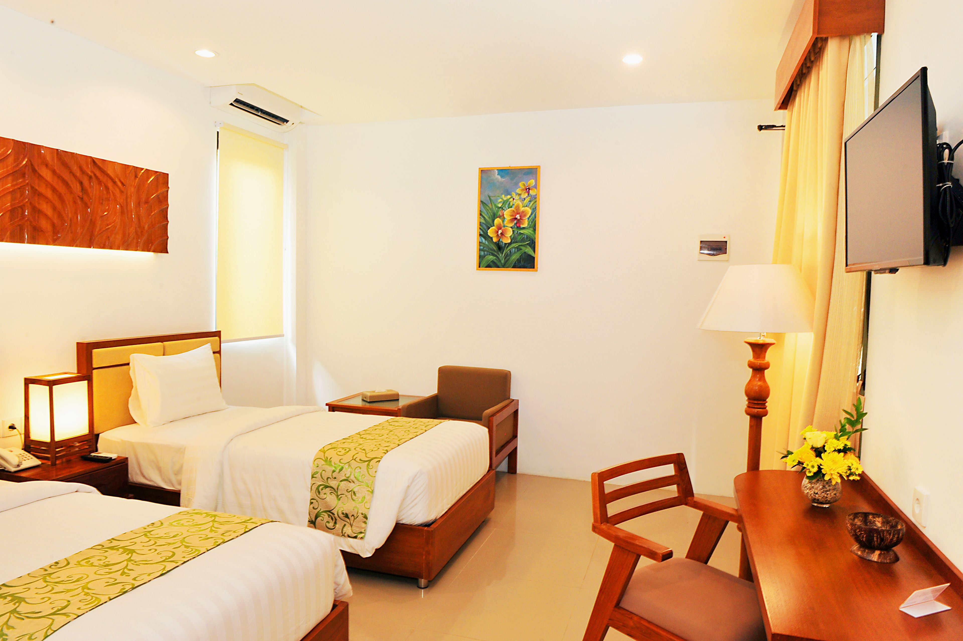 Une chambre d’hôtel avec deux lits, un bureau, une chaise, une télévision et un tableau au mur.