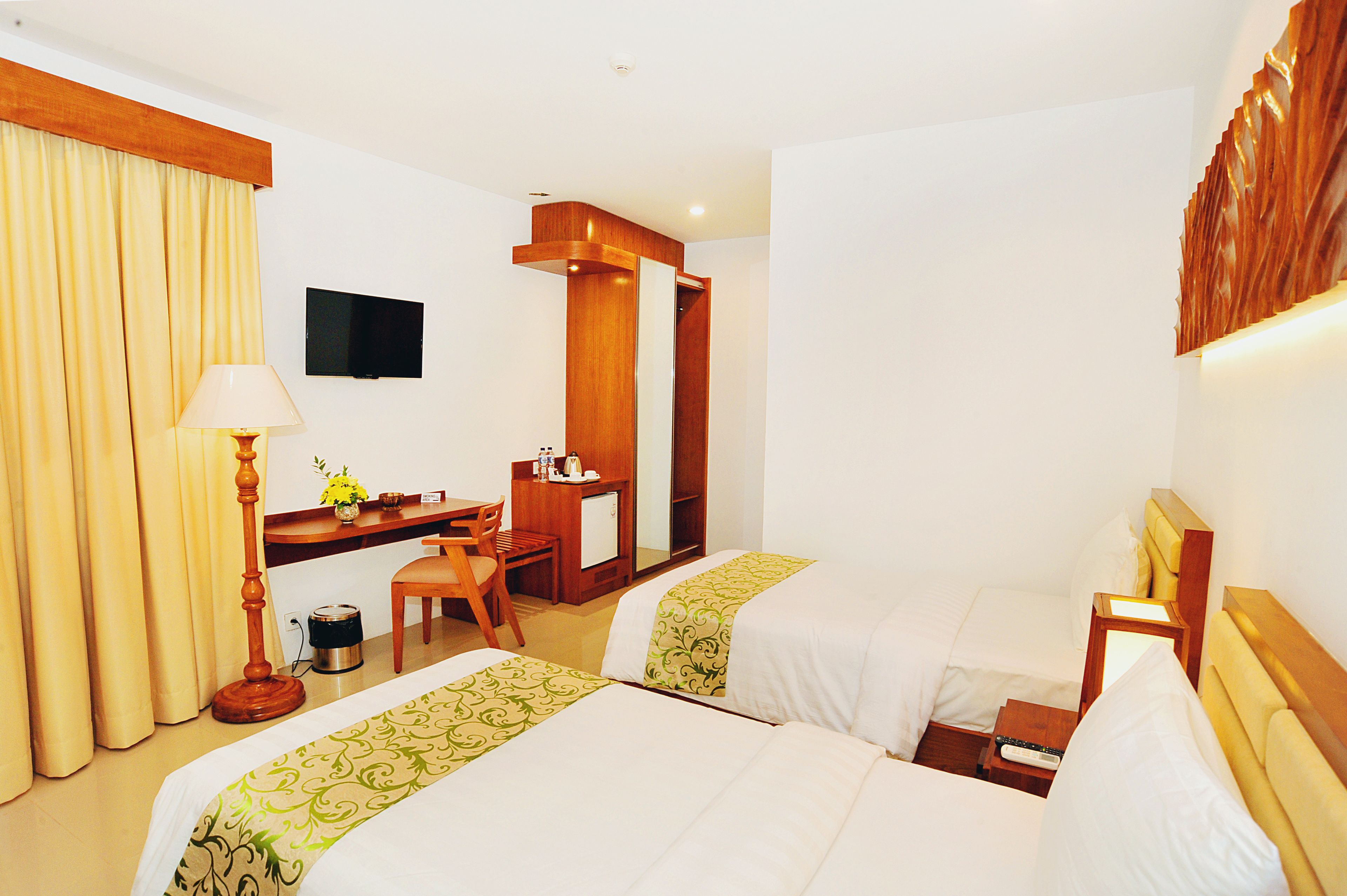 Habitación de hotel con dos camas, un escritorio, una silla, un televisor y un espejo.