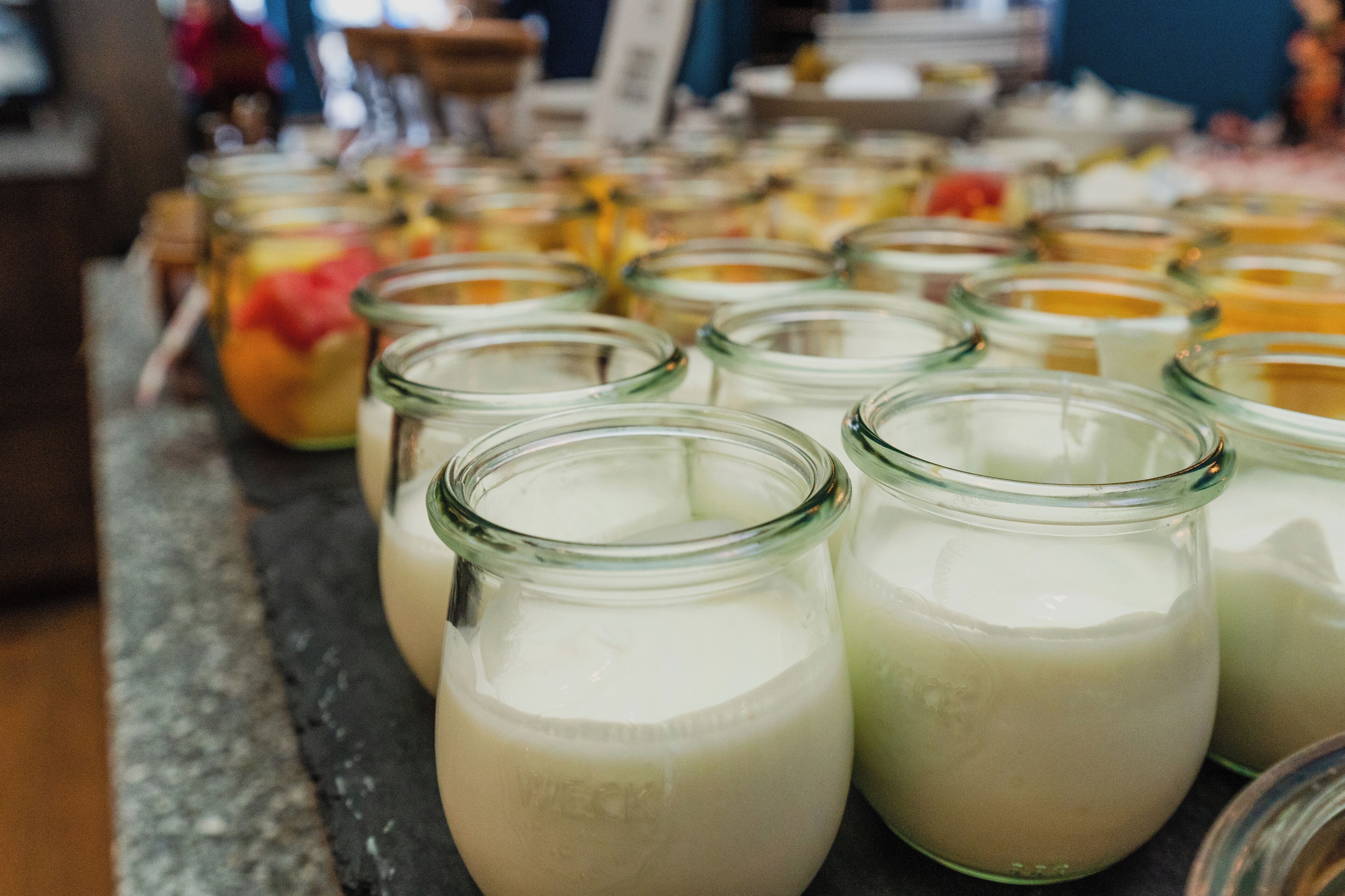 Multiple glass jars filled with a white liquid, likely dairy products, arranged on a table.
