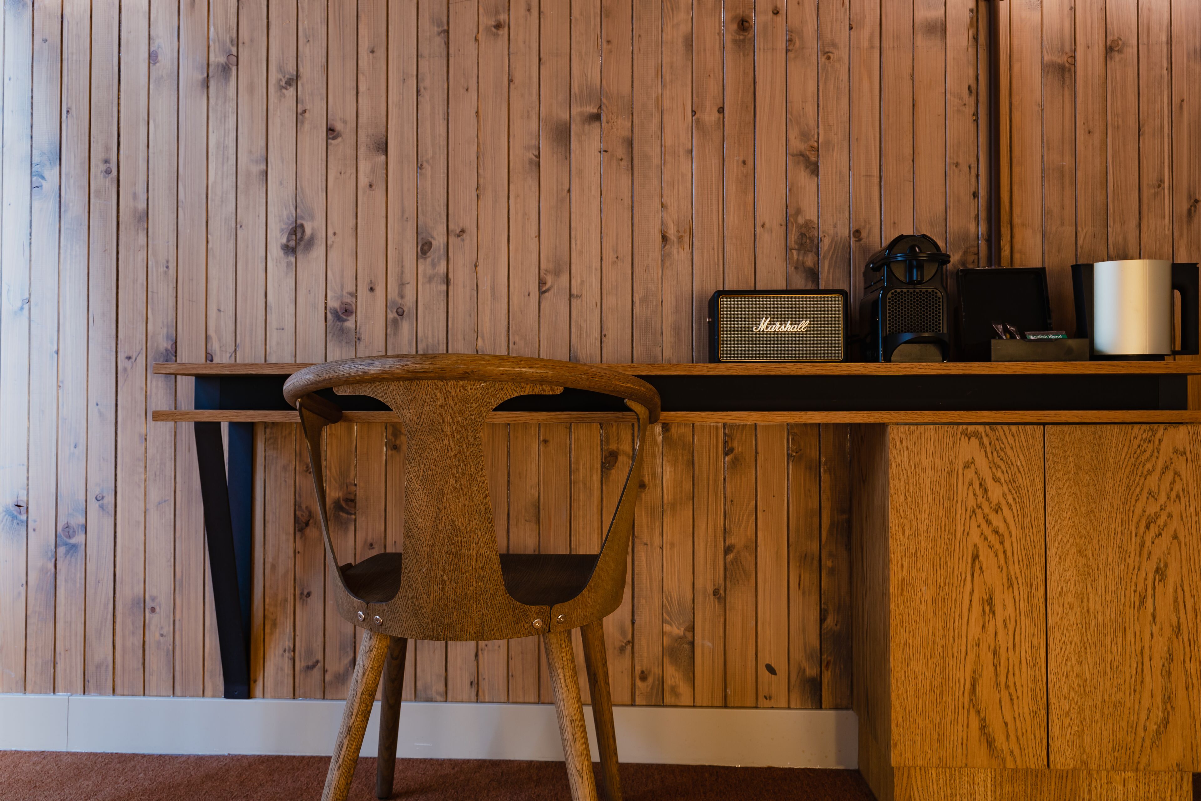 A wooden bar area with a vintage radio, a coffee maker, and a white mug on the counter.