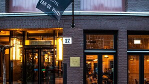 Een hotel ingang met een bord waarop 'Hotel Van De Vleugel' en het nummer 17 staat.