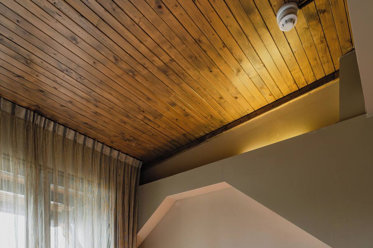 Una cama grande con sábanas blancas en una habitación con vigas de madera en el techo y un cabecero moderno.