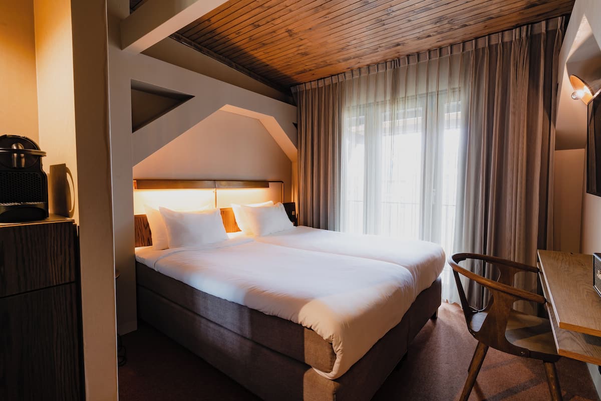 Una habitación de hotel con una cama grande, un escritorio y una silla.