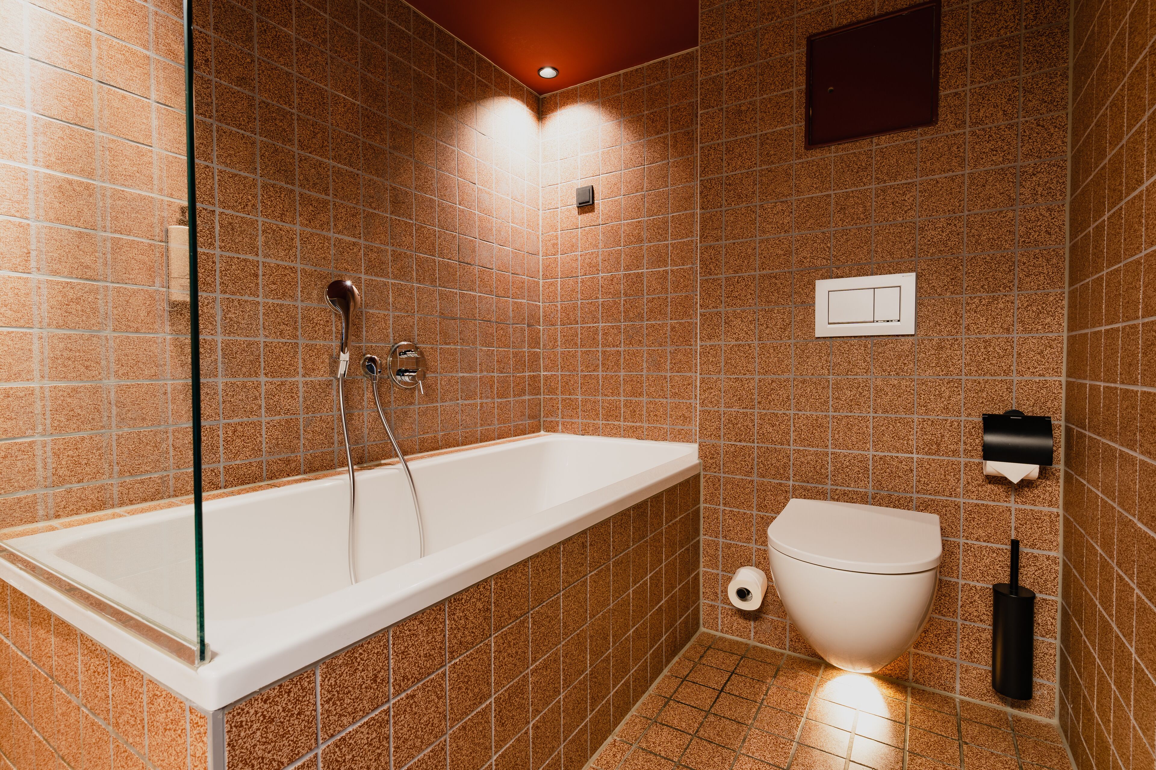 A modern bathroom with a bathtub, toilet, and hand dryer.