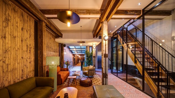 Een modern interieur met een houten wand, een bank, een bijzettafeltje en een trap.