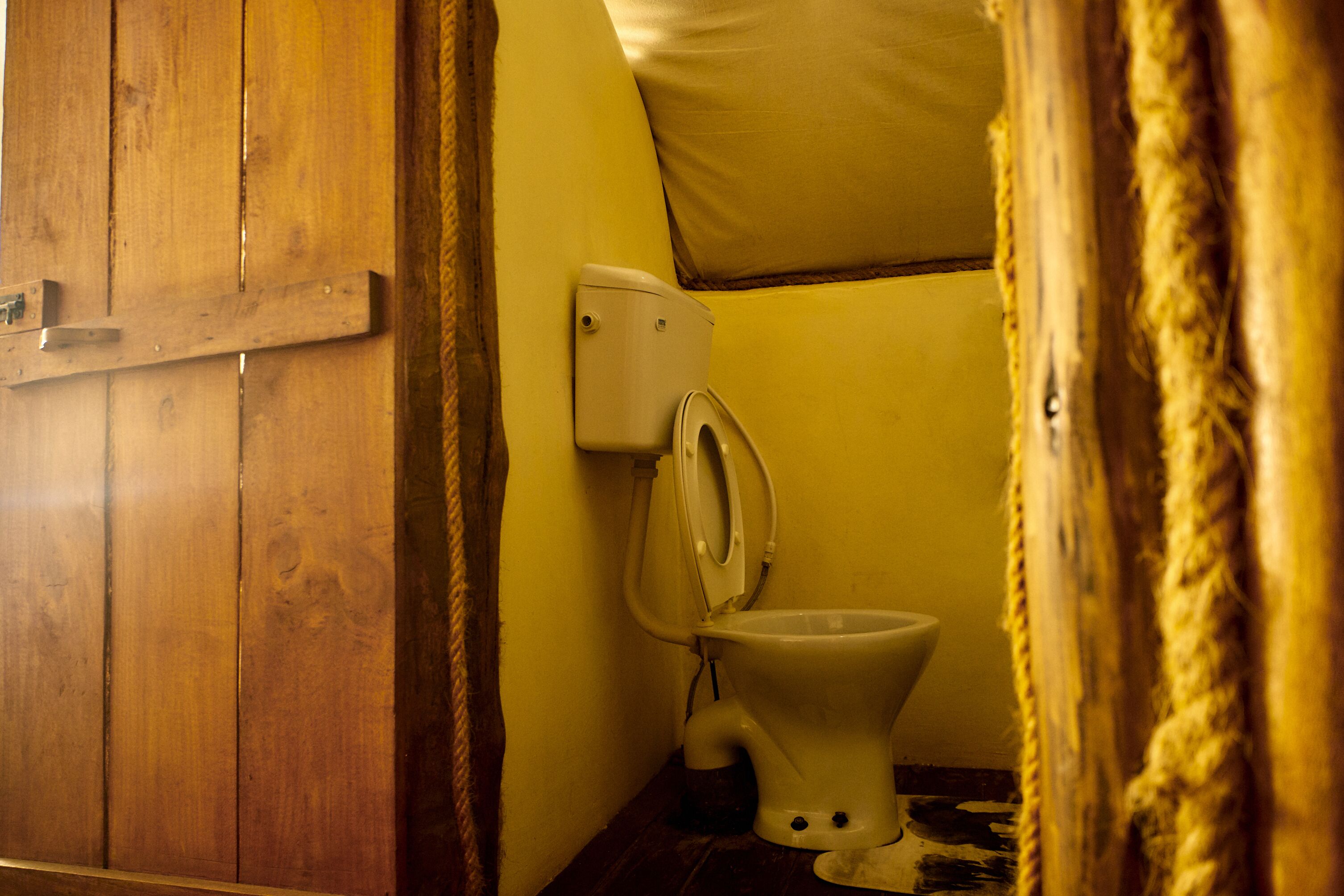 A small, compact bathroom with a wooden door, a toilet, and a wall-mounted bidet.