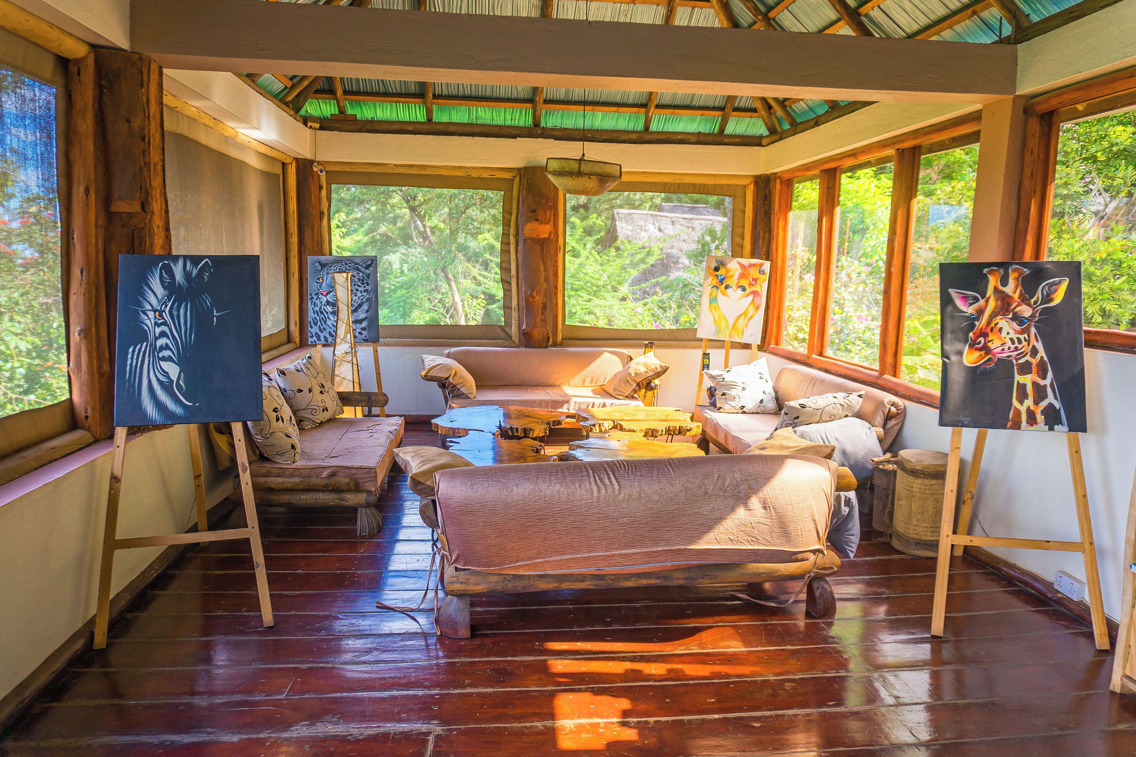 Una habitación acogedora con piso de madera, un sofá, una mesa de centro y cuadros sobre caballetes.