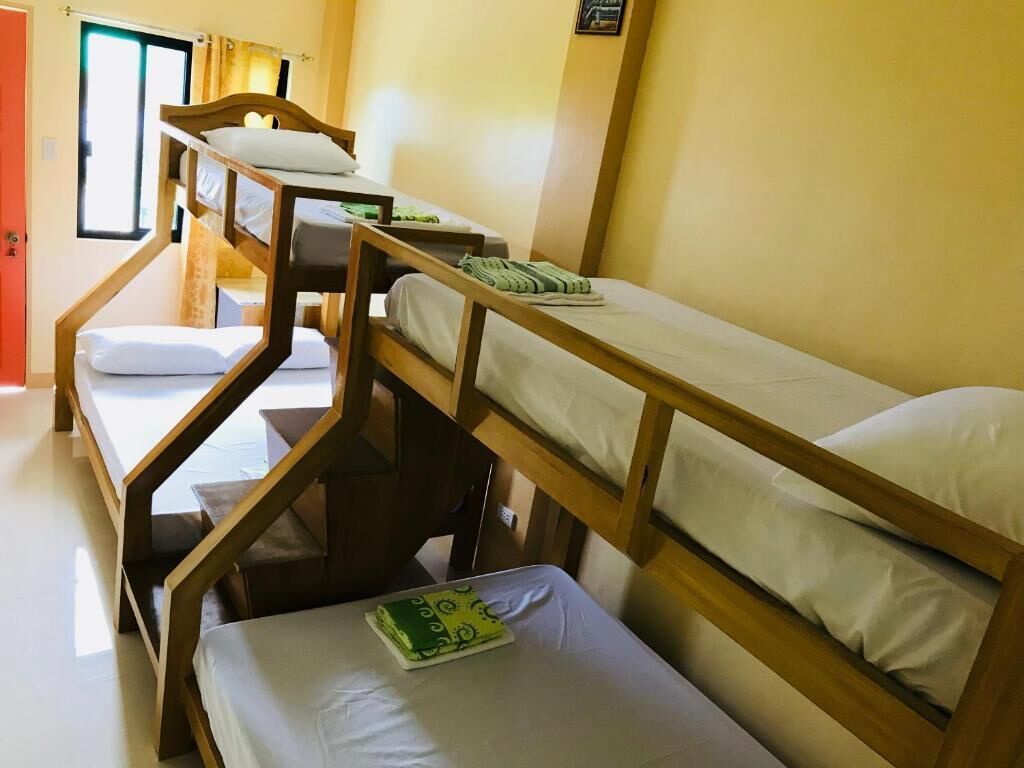 A room with bunk beds, a window, and a door.