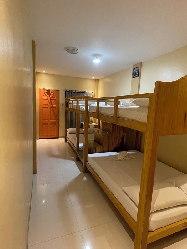 A room with bunk beds, a wooden door, and a ceiling light.