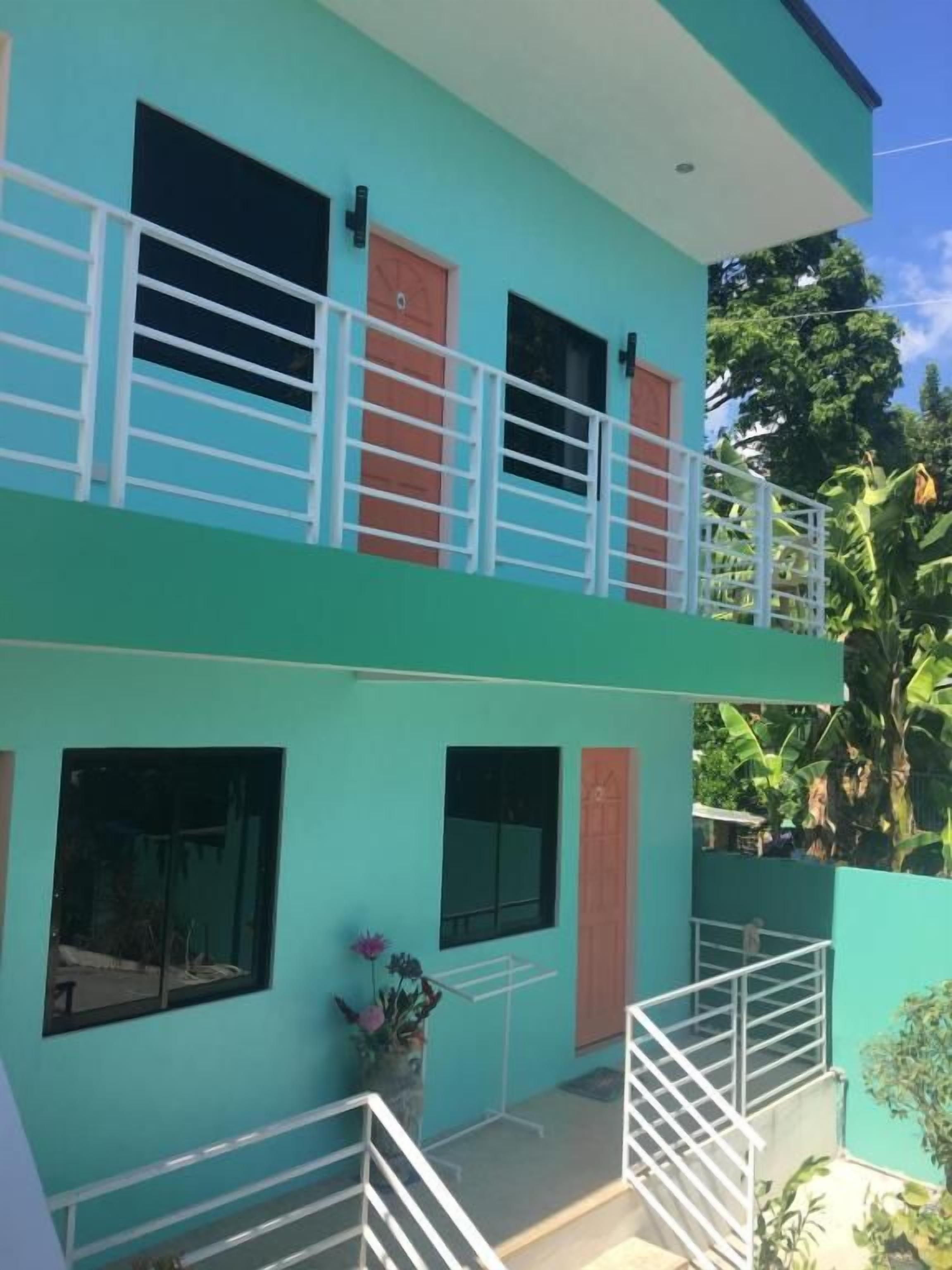 A two-story building with a balcony, windows, and a door.