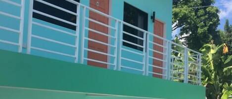 A two-story building with a balcony, windows, and a door.
