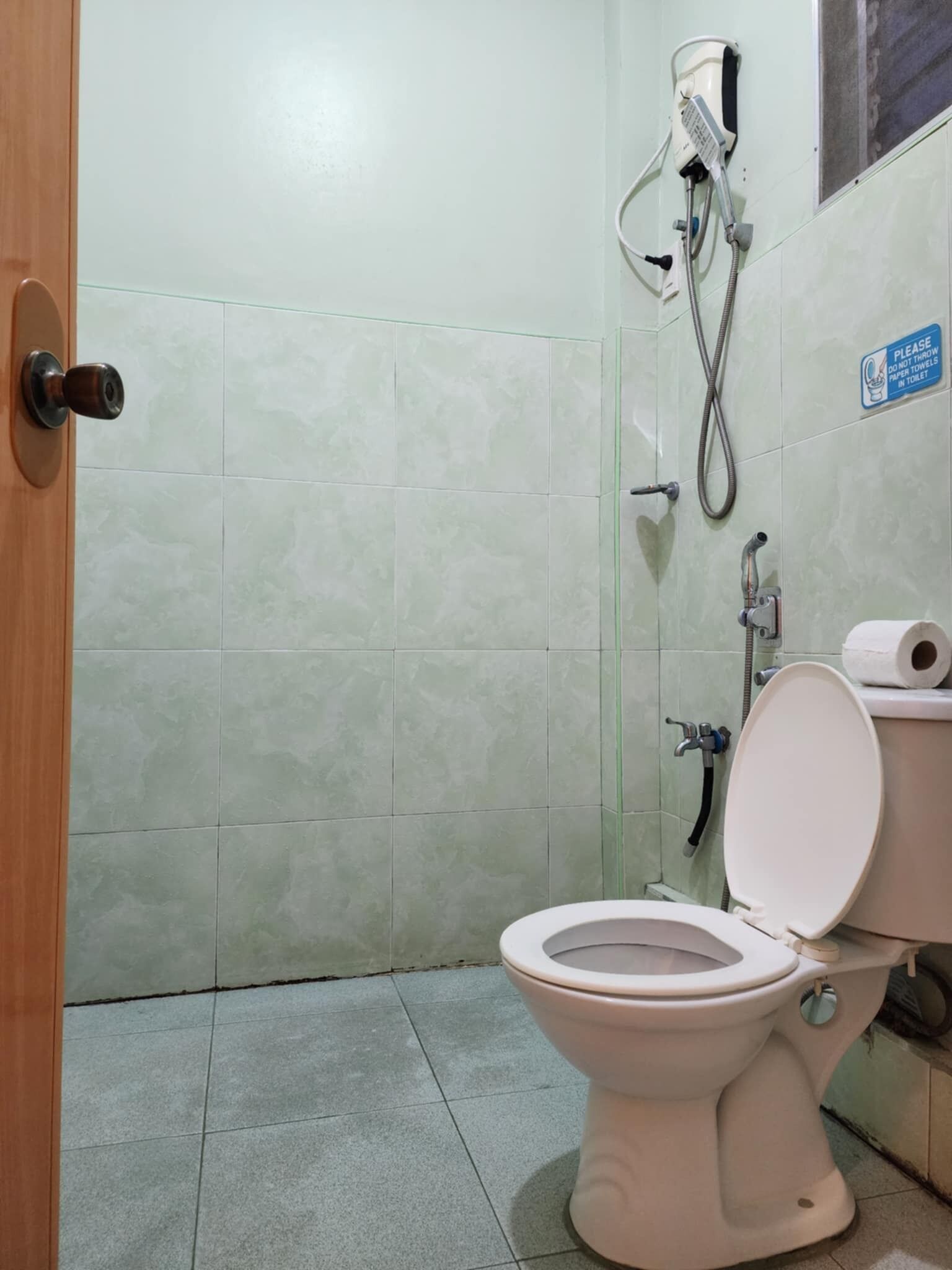 Un baño pequeño con inodoro, ducha y un cartel que indica no tirar toallas de papel en el inodoro.