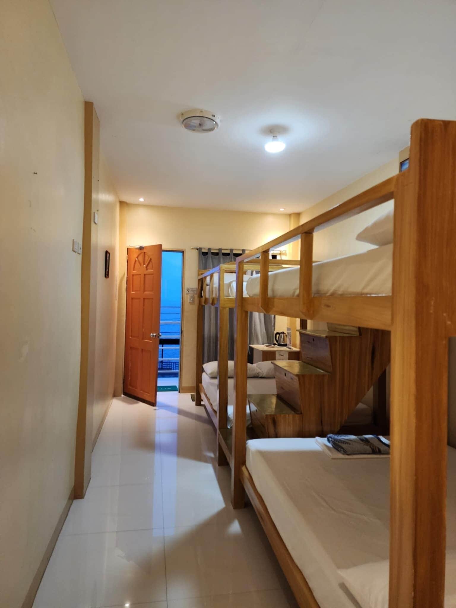 A hotel room with bunk beds, a door leading to a balcony, and a tiled floor.
