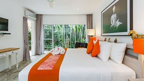 Habitación de hotel con una cama grande, ventilador de techo, televisor, ventana con cortinas e imagen enmarcada en la pared.