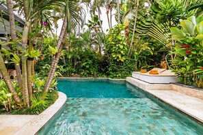 A pool surrounded by lush tropical plants and palm trees. - Villa Eindra (Seminyak)