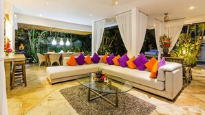 Una sala de estar moderna con un sofá seccional, una mesa de centro de vidrio y un comedor con una mesa y sillas.