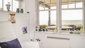 Una habitación con vista al mar, un radiador blanco, una radio y varios objetos decorativos en el alféizar de la ventana.