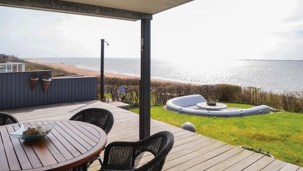 Un espacio al aire libre cubierto con una mesa, sillas, una parrilla y vistas a la playa.