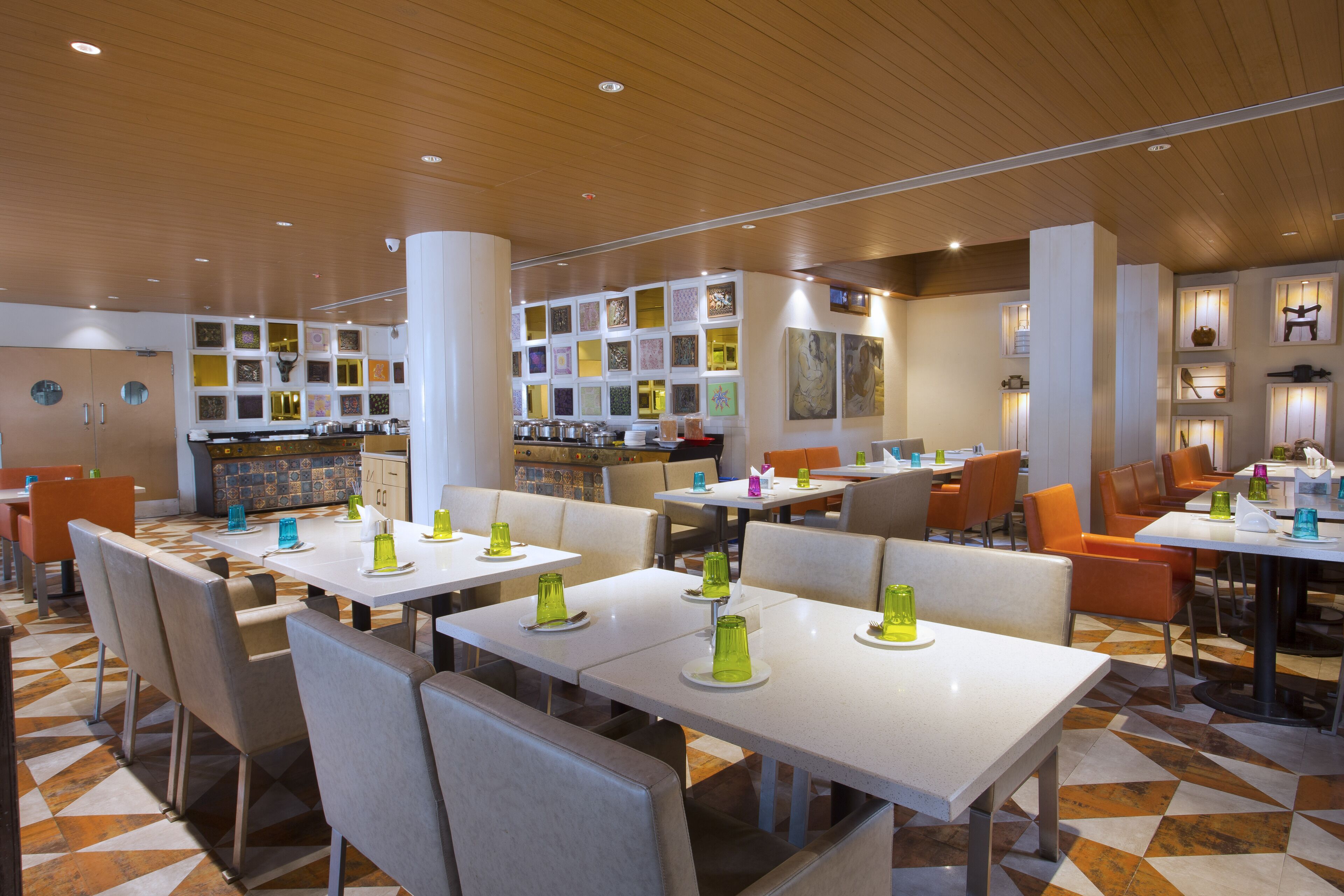 Un restaurante moderno con mesas y sillas blancas, suelo estampado y variados adornos en las paredes.