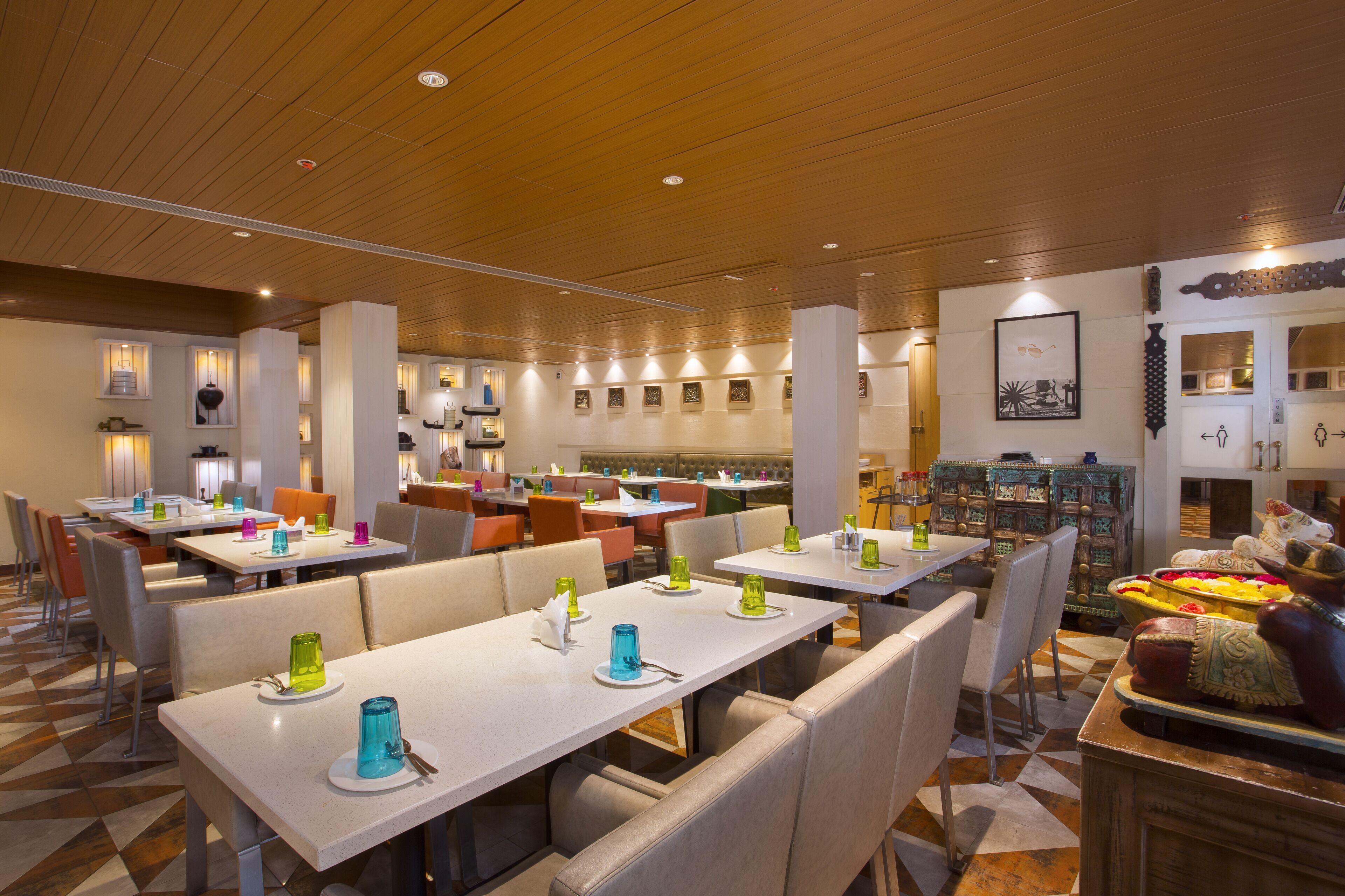 A spacious restaurant with multiple dining tables and booths, wooden ceiling, and various wall decorations.