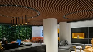 A modern interior with a reception desk, seating area, and a green wall. - Fountain Tree by TGI (Bengaluru)