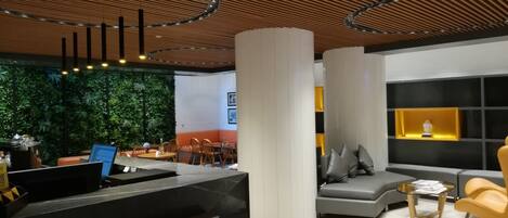 A modern interior with a reception desk, seating area, and a green wall.